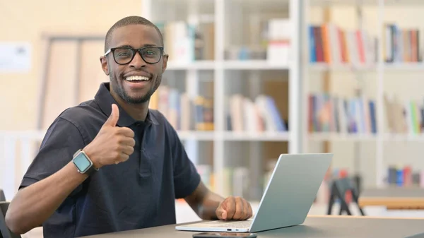 Daumen hoch von jungem Afrikaner, der in Bibliothek arbeitet — Stockfoto