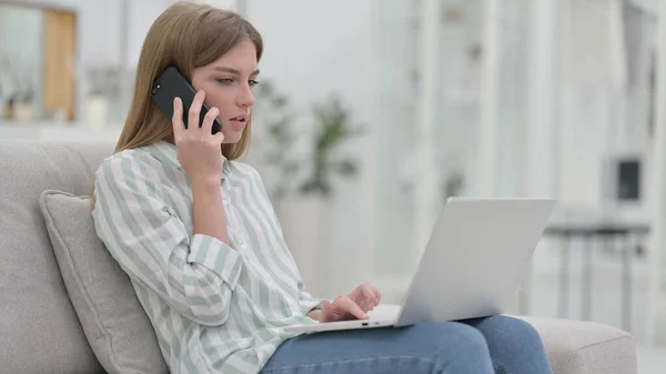 Young Woman with Laptop Talking on Phone at Home — Stock Photo, Image