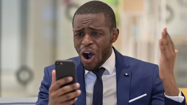Retrato del empresario africano que tiene pérdida en el teléfono inteligente —  Fotos de Stock