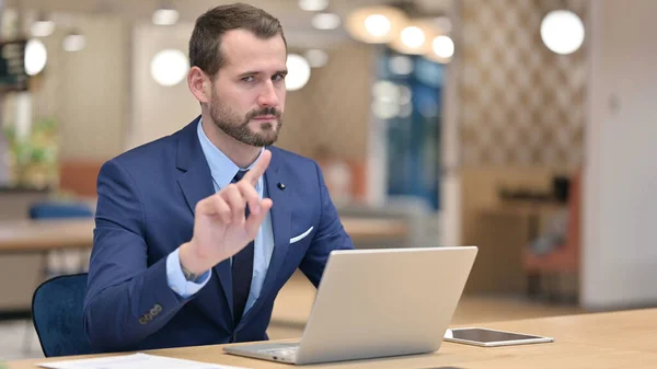 Empresário de meia-idade grave com laptop dizendo não com sinal de dedo — Fotografia de Stock