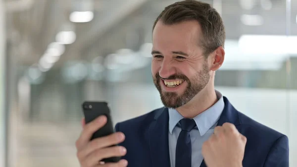スマートフォンで成功を祝う中年ビジネスマンの肖像 — ストック写真