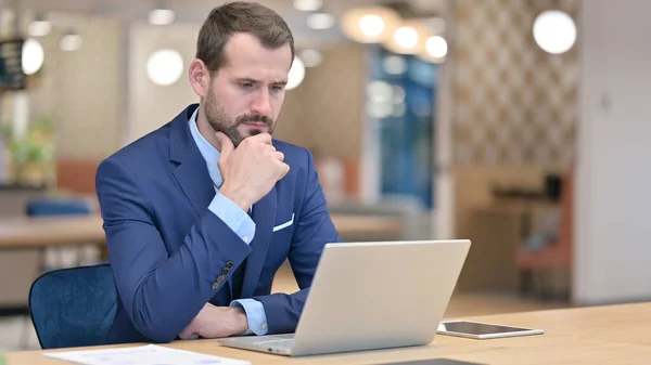 Pensive Moyen Age Homme d'affaires Penser et travailler sur ordinateur portable dans le bureau — Photo