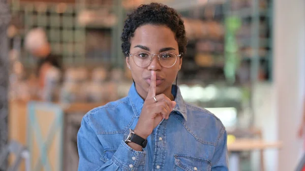 Retrato de una mujer africana seria poniendo dedo en los labios, signo silencioso — Foto de Stock