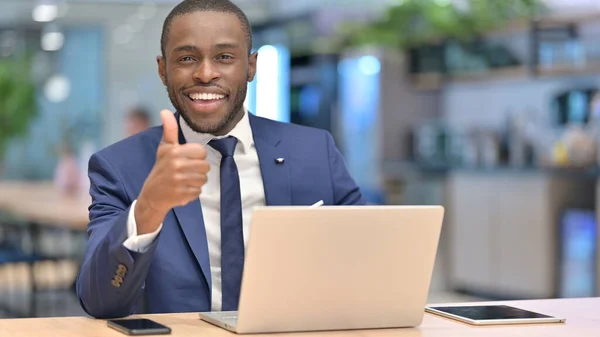 Afrikaans zakenman met laptop doet duimen omhoog in Office — Stockfoto