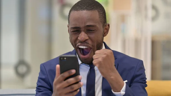 Retrato del empresario africano celebrando el éxito en Smartphone —  Fotos de Stock