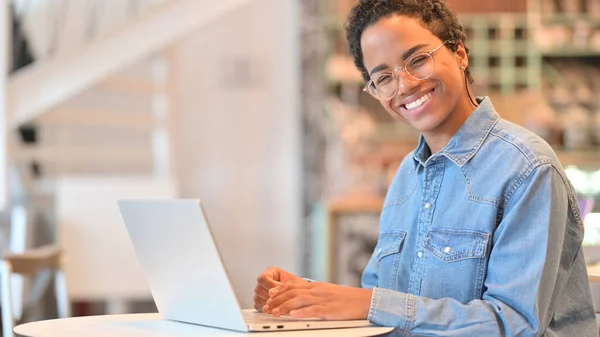 Afrikansk kvinna med laptop ler mot kameran — Stockfoto