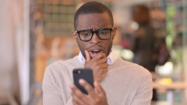 Retrato del hombre africano trastornado que tiene pérdida en el teléfono inteligente —  Fotos de Stock