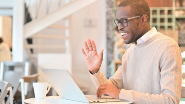 Cafe 'de laptoptan konuşan neşeli Afrikalı adam.