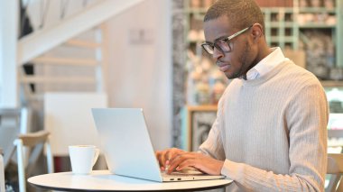 Cafe 'de laptopla çalışan odaklanmış Afrikalı Adam