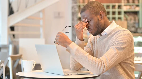 Gestresste Afrikaanse man met laptop met hoofdpijn in Cafe — Stockfoto