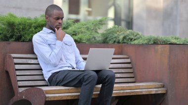 Afrikalı Adam Laptop 'u dışarıda düşünüyor ve kullanıyor 