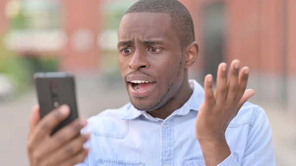 Retrato de homem africano perturbado com perda no smartphone — Fotografia de Stock