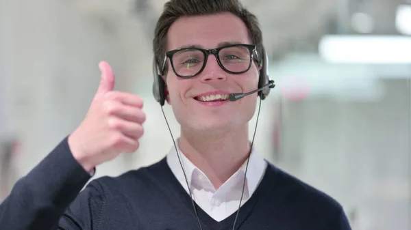 Junger Geschäftsmann mit Headset zeigt Daumen hoch — Stockfoto