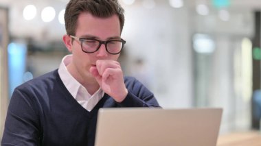 Laptop öksüren hasta genç iş adamı.