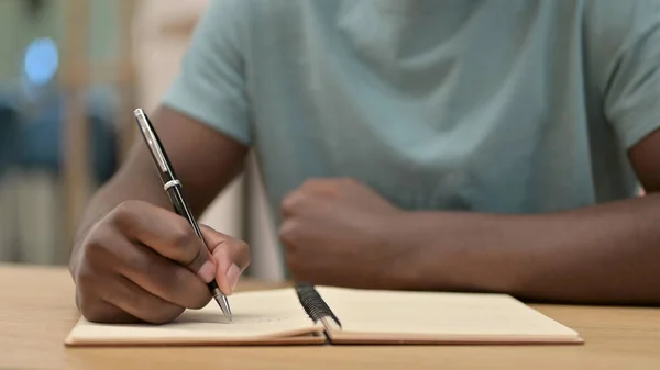 Κλείσιμο του African Man Writing στο Notebook — Φωτογραφία Αρχείου