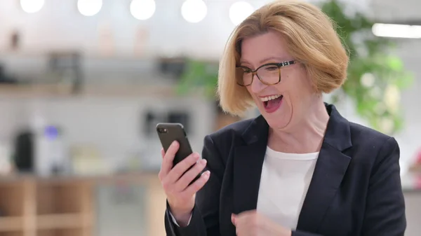Retrato de la vieja empresaria emocionada celebrando el éxito en el teléfono inteligente — Foto de Stock
