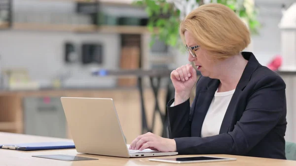 Vecchia imprenditrice con tosse per computer portatile in ufficio — Foto Stock