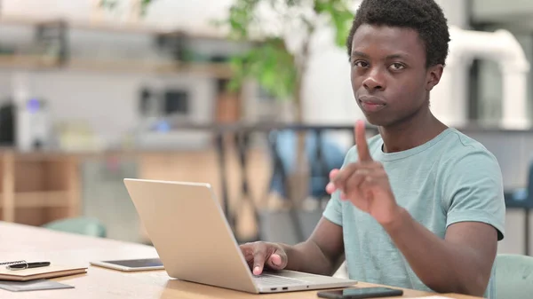Allvarlig ung afrikansk man med bärbar dator säger nej med Finger Sign — Stockfoto