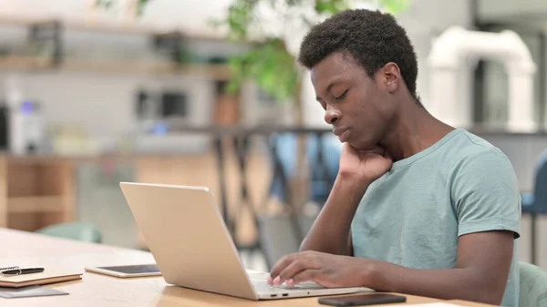 疲惫的非洲年轻人，膝上型电脑有颈部疼痛 — 图库照片
