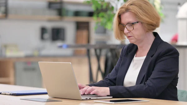 Old Businesswoman working on Laptop in Office