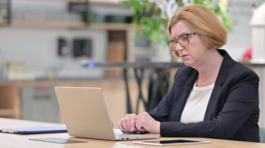 Eski iş kadınının ofiste dizüstü bilgisayarı var.