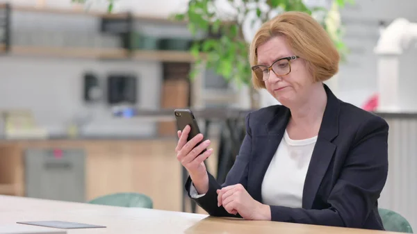 Vieja empresaria que tiene un fallo en el teléfono inteligente en la oficina — Foto de Stock