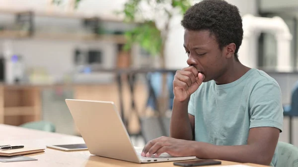 Sjuk ung afrikansk man med laptop hosta — Stockfoto