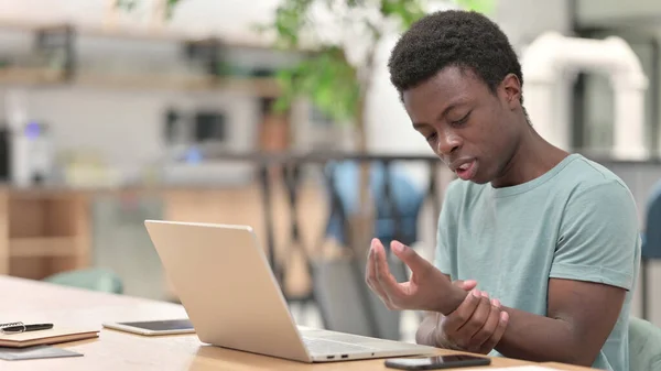 Ung afrikansk man med bärbar dator med handledssmärta — Stockfoto