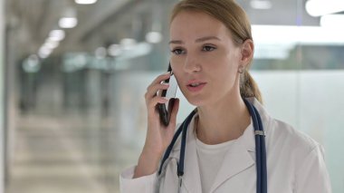 Kadın doktor telefonda konuşuyor, müzakere yapıyor.