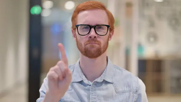 Vážný mladý rusovlasý muž říká ne podle znaku prstu — Stock fotografie