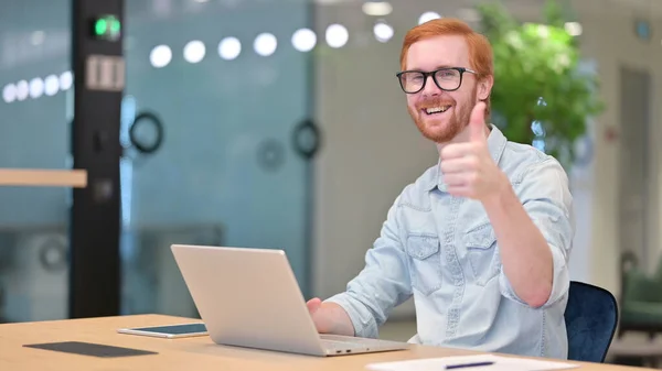 Pollici su da giovane rossa uomo lavorando su computer portatile in ufficio — Foto Stock