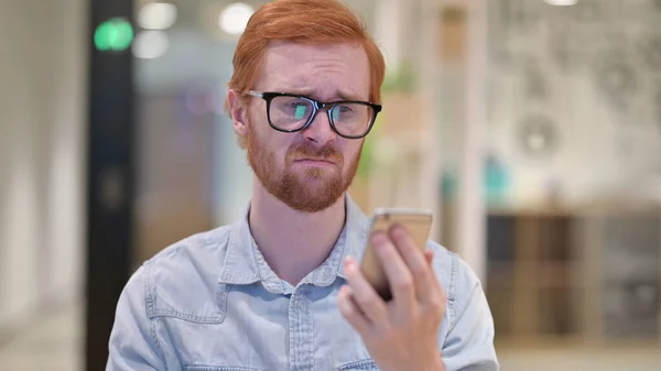 Jonge roodharige Man reageert op Online Loss op Smartphone — Stockfoto