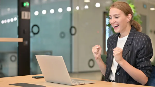 Красивая молодая предпринимательница празднует успех на ноутбуке в офисе — стоковое фото