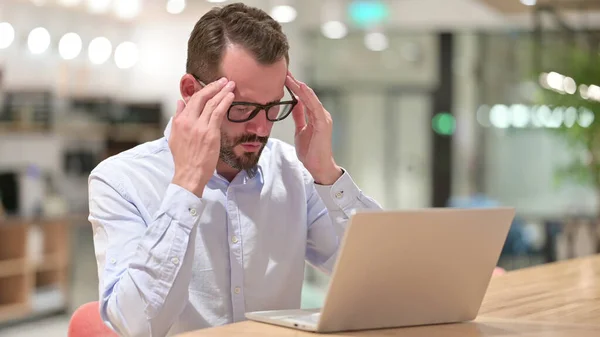 Zestresowany biznesmen z laptopem z bólem głowy w biurze — Zdjęcie stockowe