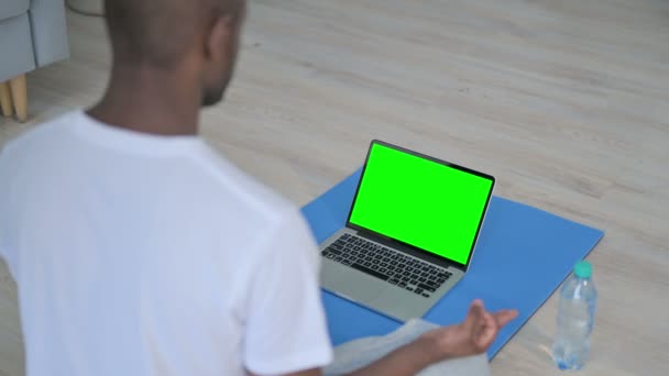 Achteraanzicht van Afrikaanse Man die Yoga terwijl het kijken naar Laptop met Chroma Zeer belangrijk Scherm doet — Stockvideo