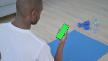 Afrikalı Adam Yoga Mat 'te Krom Anahtar Ekranı ile Akıllı Telefon Kullanıyor