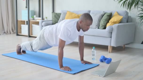 Homem Africano Olhando para Laptop enquanto faz Pushups no tapete de Yoga — Vídeo de Stock