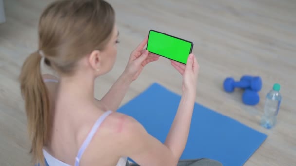 若い女性の背面ビューヨガマットのクロマキー画面でスマートフォンを見て — ストック動画