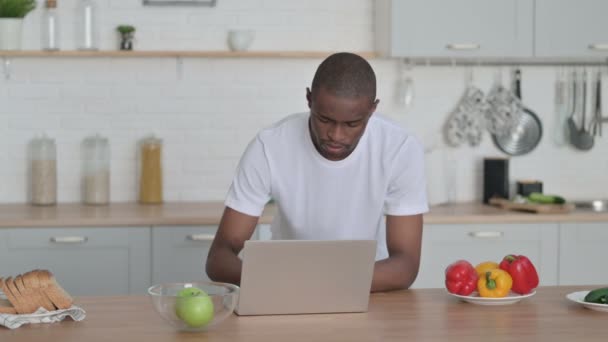 Αφρικανός που εργάζεται στο lap-top στην κουζίνα — Αρχείο Βίντεο