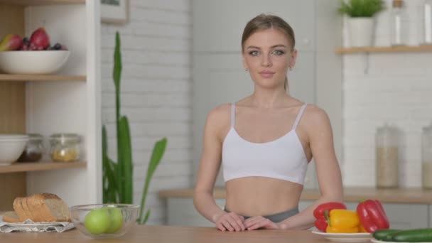 Sportovní žena ukazuje palce nahoru, zatímco stojí v kuchyni — Stock video