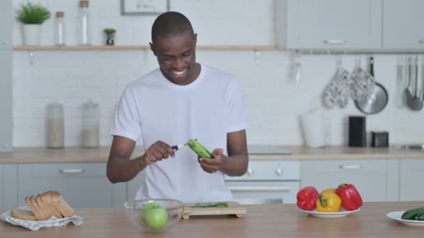 Friska afrikanska mannen Peeling gurka i köket — Stockvideo