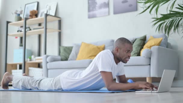 Afrikalı Adam Yoga Mat 'te dizüstü bilgisayar kullanıyor. — Stok video