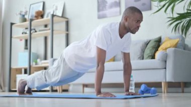 Genç Afrikalı adam evde yoga yaparken şınav çekiyor.
