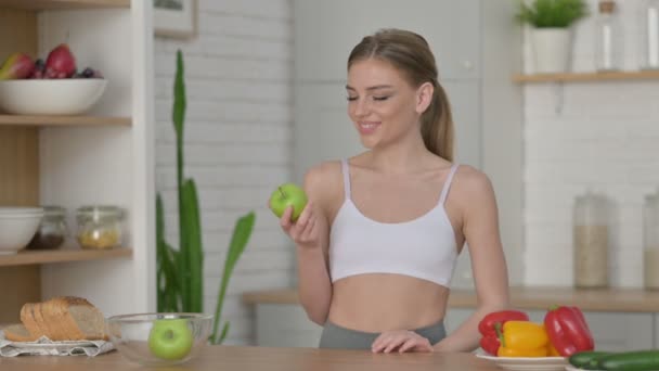 Sportos nő felbukkan hüvelykujját, miközben tartja Apple a konyhában — Stock videók