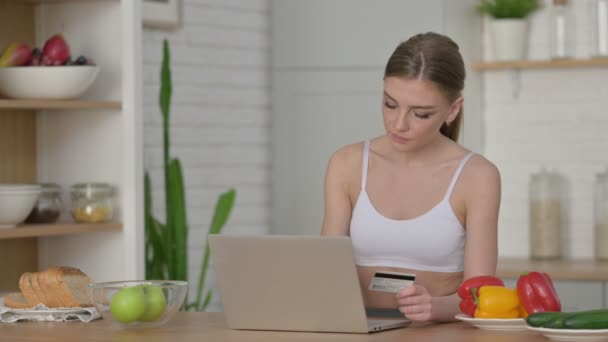 Atletisk kvinna gör online-betalning på laptop i köket — Stockvideo