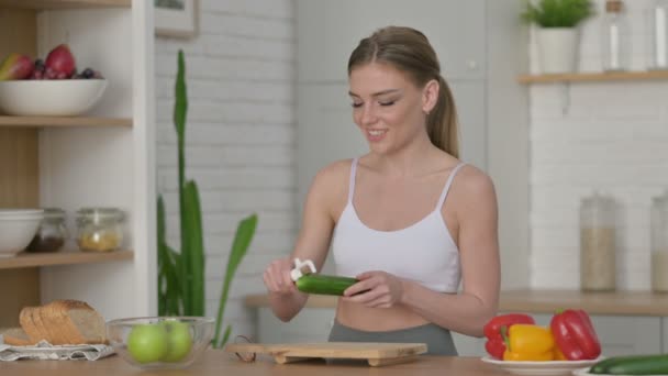 Gesunde Frau schält Gurke, während sie in der Küche steht — Stockvideo