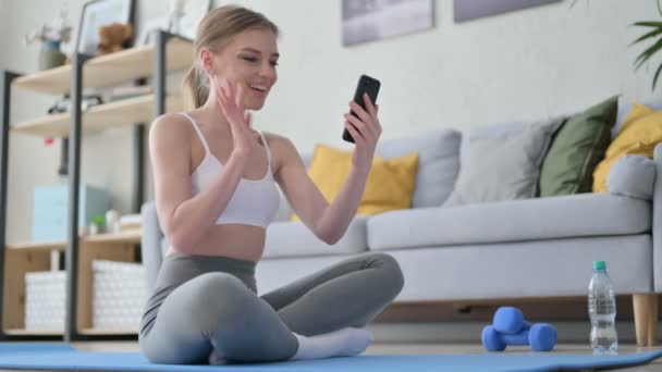 Mujer hablando en videollamada en Smartphone mientras está sentada en Yoga Mat — Vídeo de stock