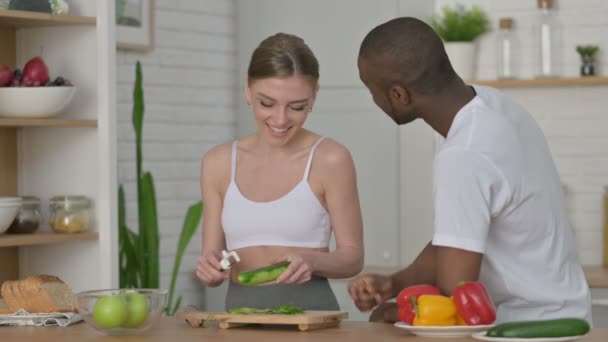 Sportig kvinna Peeling grönsaker med afrikansk man i köket — Stockvideo