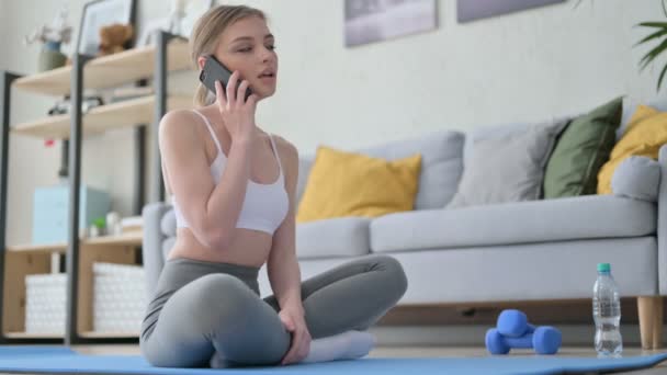 Jonge vrouw praten op Smartphone op Yoga Mat thuis — Stockvideo