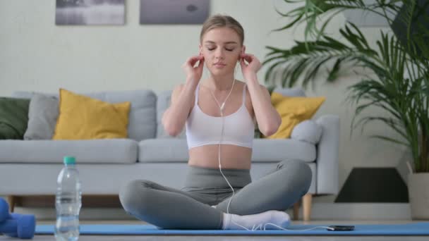 Молодая женщина слушает музыку на наушниках и медитирует — стоковое видео